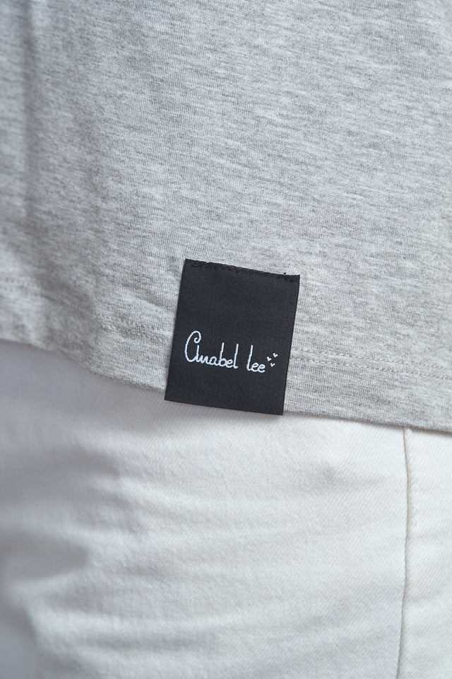 Detalle del logo bordado en el pecho de la camiseta gris.