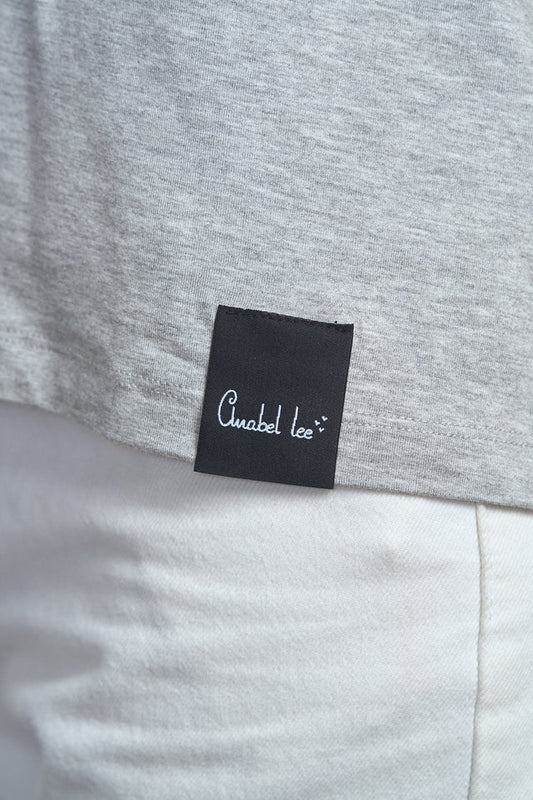 Detalle del logo bordado en el pecho de la camiseta gris.
