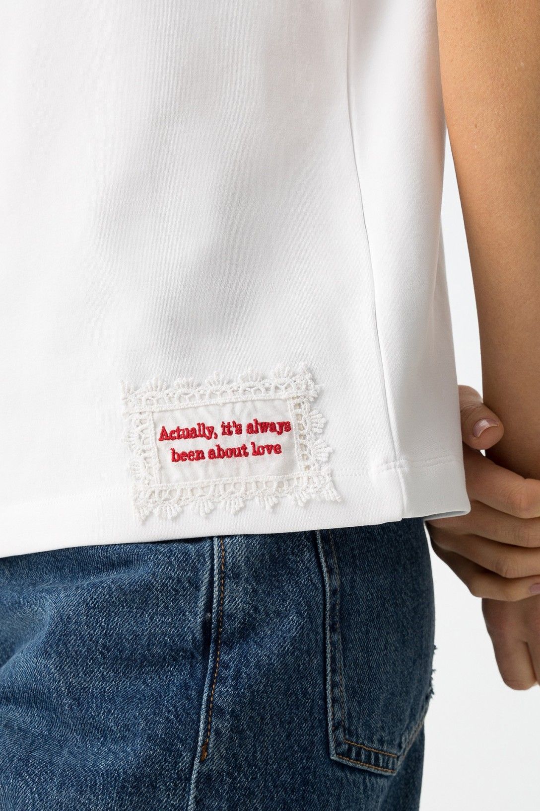 Detalle del bordado lateral en camiseta blanca Aura