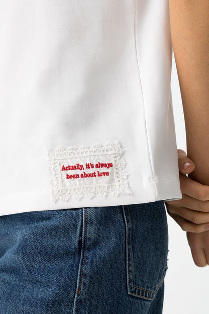 Detalle del bordado lateral en camiseta blanca Aura