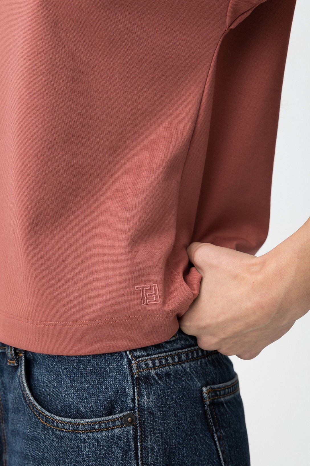 Detalle del bordado minimalista en el bajo de la camiseta rosa