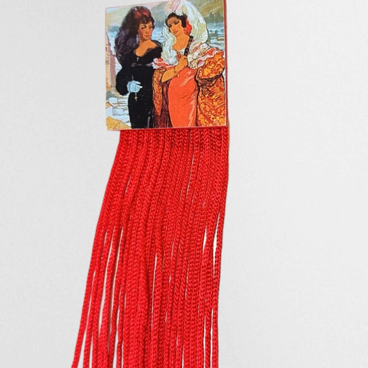Detalle de los flecos rojos vibrantes del broche cuadrado de flamenca