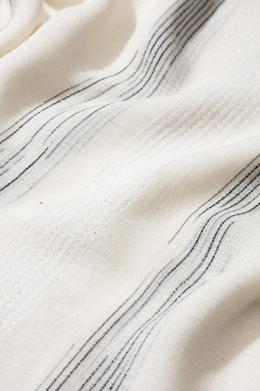 Detalle de los hilos metálicos plateados en pañuelo blanco