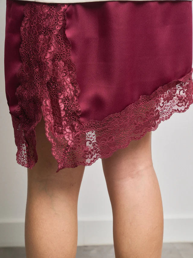 Bajo del vestido con falda satinada y terminación de puntilla fina.