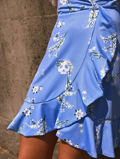 Estampado calaveras floral detallado sobre fondo azul de vestido fluido.
