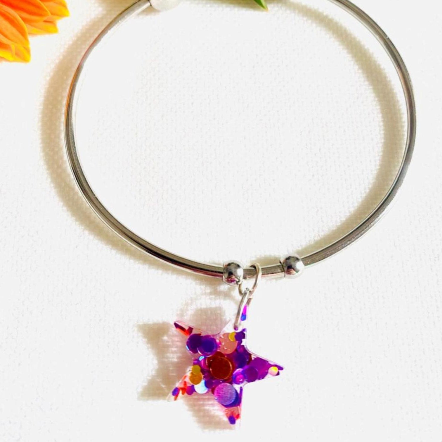 Pulsera artesanal con estrella rosa de purpurina hecha por María del Mar