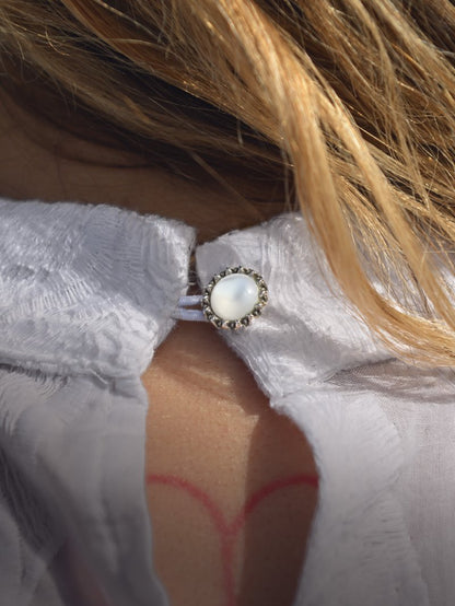 Detalle del botón joya en camisa blanca romántica
